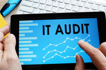 Man holding IT audit report in a tablet.