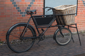 Fototapeta na wymiar An old vintage delivery bike standing and complete with a wicker basket on the front