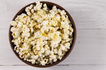 Bowl with popcorn on wooden table