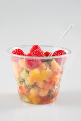 glass bowl with fresh fruits salad berries isolated on grey