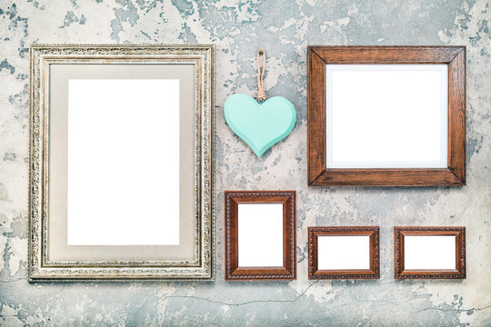 Photo or picture frames blanks and handmade wooden love heart hanging on vintage aged grunge textured concrete wall background. Retro old style filtered photo