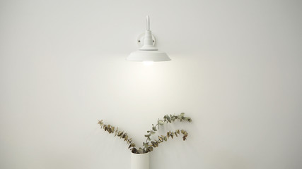 Wall lamp and dried eucalyptus branches in vase with white wall