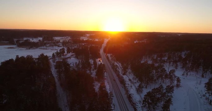 Car on a winter road, Cinema 4k aerial view following a car above a frozen archipelago route and the sunset above a town, in sarkisalo, Varsinais-suomi, Finland