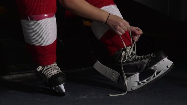 woman hockey player ties skate laces low moving angle