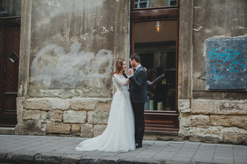 Wedding couple walks in the old city. Stone walls of ancient town on background. Rustic bride with...