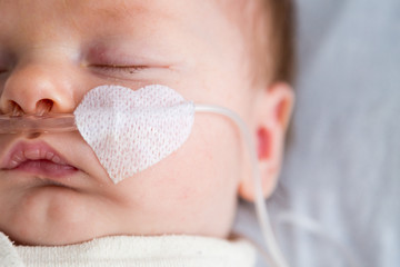 Newborn baby in hospital weakened with bronchitis is getting oxygen via nasal prongs to assure oxygen saturation - 191968034