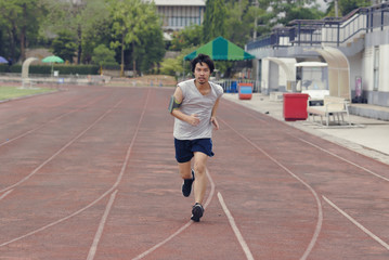 Obraz premium Handsome athlete Asian man running on racetrack in stadium with copy space background. Healthy active lifestyle concept.