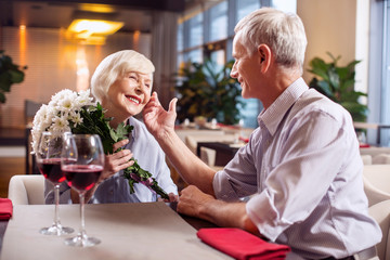 Forever love. Sweet cheerful mature couple having date while smiling and man touching woman face