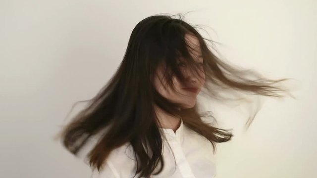 Beautiful young woman turning around and fluttering hair with wind. Slow motion.
