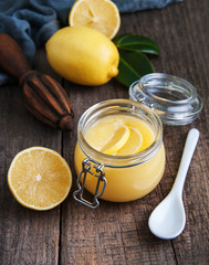 Lemon curd in glass jar with fresh lemons