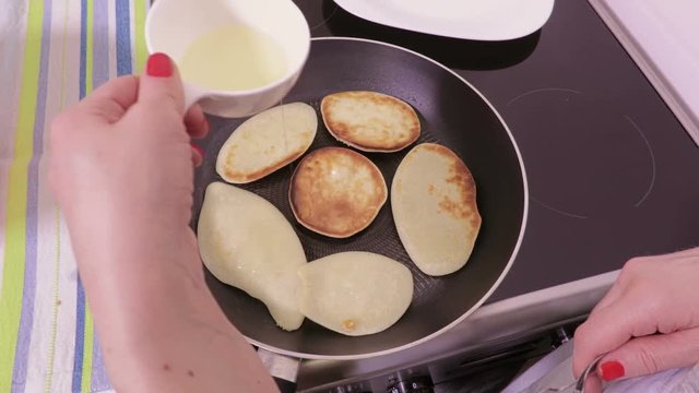 Woman cooking pancakes and add oil