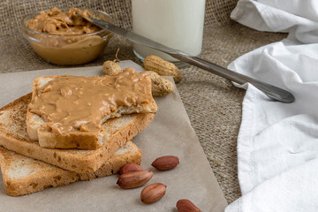 Bitten peanut butter sandwich, toasted bread, peanuts
