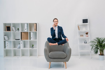 young businesswoman talking by smartphone and smiling at camera while levitating in office