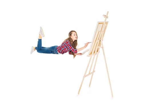 girl levitating and painting on easel isolated on white