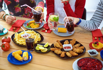 Top view of group of people having dinner together while sitting at wooden table. Food on the table. People eat fast food.