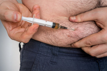 Diabetic man with syringe inject insulin to his belly