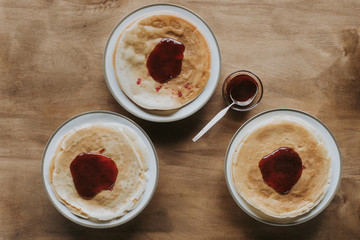 top view of tasty homemade pancakes with jam on wooden table