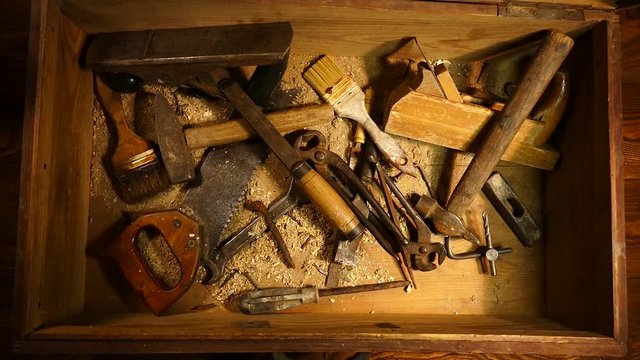 Old hand tool in a wooden chest. Retro tool. Rusty pliers, hammer, file, saw. Old wooden tool box..
