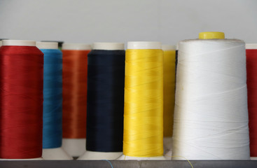 Colorful thread in the thread roll, yellow color, red, white, blue, orange and dark blue. Through the use already from sewing garment and prepare to use again.