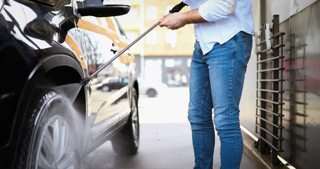 Person washing his car in carwashin jet with cleaner