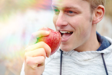 handsome man eating a red apple