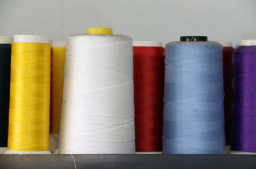 Colorful thread in the thread roll, white color, blue, red, yellow and purple. Through the use already from sewing garment and prepare to use again.