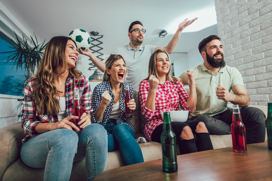 Happy friends or football fans watching soccer on tv and celebrating victory at home.Friendship, sports and entertainment concept.