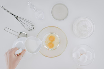 cropped shot of person pouring milk while cooking pancakes isolated on grey
