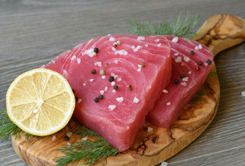 Raw tuna fillet with dill, lemon and in olive cutting board