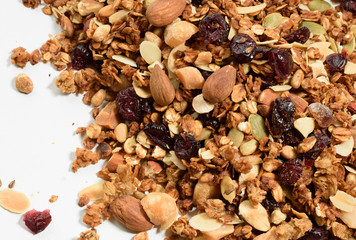 Pile of homemade granola with various seeds and berries shot from above isolated on white background