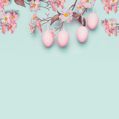 Easter layout with hanging pastel pink eggs and spring blossom at light at blue turquoise...