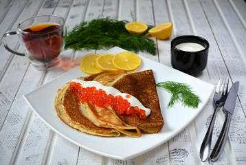 Pancakes with red caviar on plate. Russian cuisine. Maslenitsa