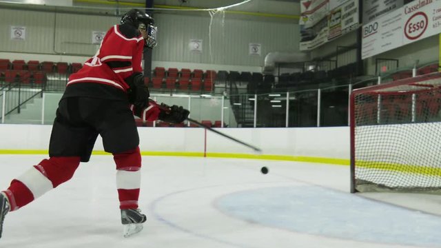 woman hockey player working on skating and shooting skills on ice view with depth of field