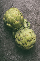 Green organic artichokes on gray granite table, top view. Healthy dieting and antioxidant vegetables