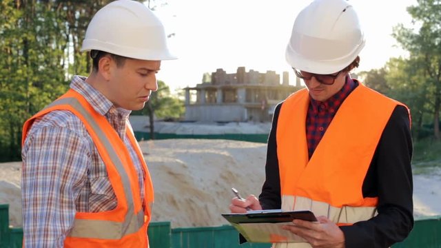 Two construction engineers discuss the construction of a residential house on the construction site