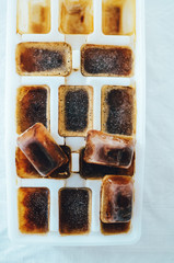 Ice cubes made with coffee in ice cube tray to prepare refreshing coffee drinks, white background