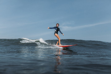 woman having fun and riding wave on surf board in ocean