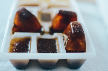 Ice cubes made with coffee in ice cube tray to prepare refreshing coffee drinks, close up on white background