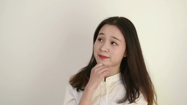 Women Facial Expression. A beautiful young woman with long hair has a question and makes a gesture with her hands. She is dressed in a white shirt.