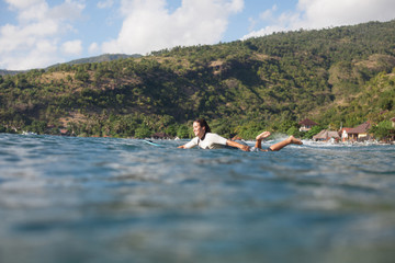 Fototapeta na wymiar woman swimming on surf board in ocean, coastline on background
