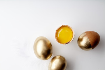 Eggs painted golden with yolk in egg stand on white background. Easter tradition concept, copy space