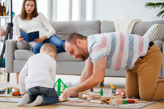 Family picture of father and son playing on floor in toy road with cars