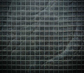 Metal mesh on black stone wall background in the dark