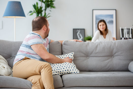 Family photo of man sitting back on couch and wife behind sofa