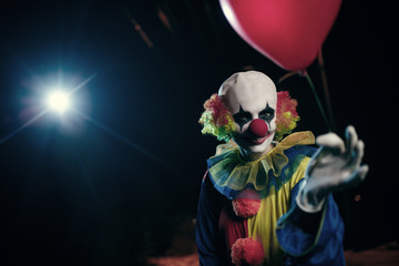 Image of clown with red balloon on background of burning lantern