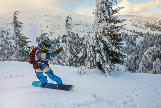 Snowboarder rides down on the background of wooded hills