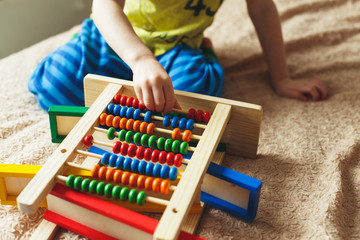Preschooler baby learns to count. Cute child playing with abacus toy. Little boy having fun indoors at home, kindergarten or day care centre. Educational concept for preschool kids.