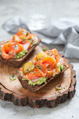 Smorrebrod with salmon on rye bread with vegetables and herbs