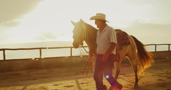 Cowboy walking his horse at sunset