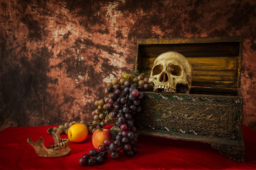 Still life with a human skull with fake apples and grapes